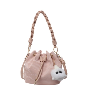 Light pink drawstring bucket bag with braided handle and plush charm on white background