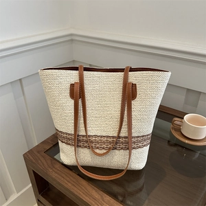 Chic woven tote bag with brown leather straps and lace trim on a wooden table