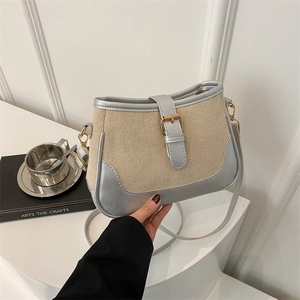 Woven silver patchwork crossbody bag with gold buckle on a clean minimalist background