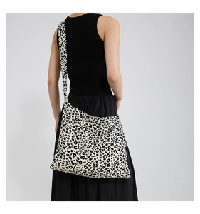 Detalle de bolso tote grande de lona con estampado de leopardo y correa ancha en modelo