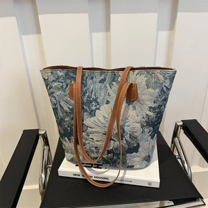Retro floral tote bag with blue jacquard fabric and brown leather handles in a minimalist setting