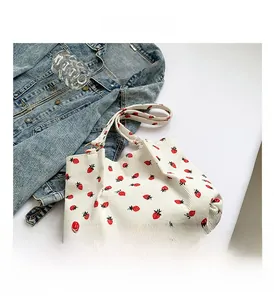 Detail shot of white corduroy tote bag featuring red strawberry patterns and spacious interior
