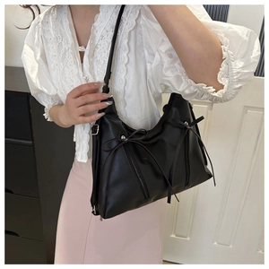 Detail of black PU leather shoulder bag with decorative bows and double zippers