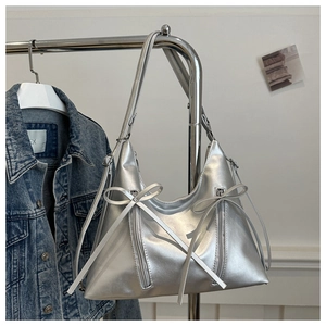 Detail of silver metallic tote bag featuring dual bows and decorative zipper accents
