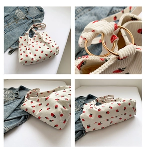 Detail view of corduroy shoulder bag showing red strawberry print and gold metal ring clips