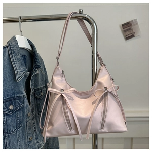 Detail of light pink shoulder bag with decorative bows and silver zippers on a rack