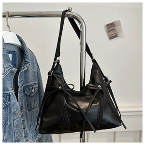 Detail of black faux leather tote bag with ribbon bow and dual vertical zippers