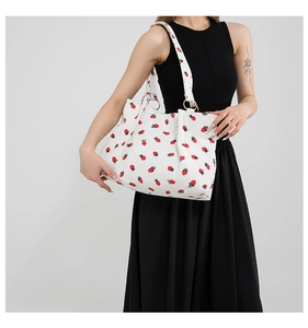 Detailed shot of white tote bag with strawberry prints and metal ring shoulder strap attachment