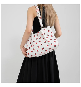 Detail of strawberry print corduroy tote bag showing gold metal rings and fabric texture