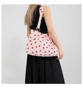 Close-up of pink corduroy tote bag featuring red strawberry patterns and metallic rings