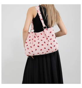Pink corduroy tote bag with strawberry prints and metal rings shown on a model