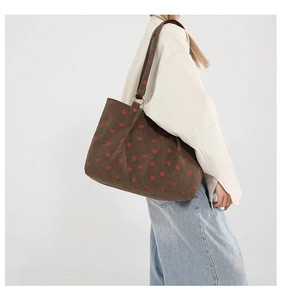 Detail view of corduroy shoulder bag showing red strawberry prints and metal rings