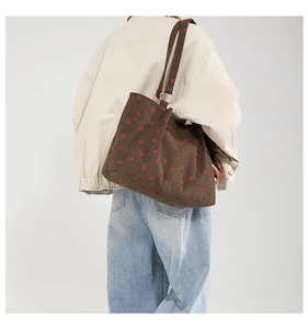 Detailed close-up of dark brown corduroy tote bag with strawberry print and gold metal rings