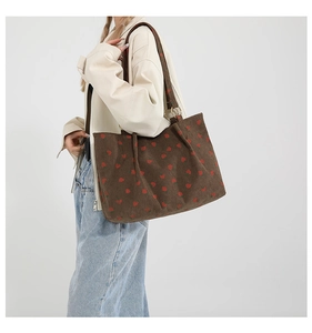 Detail of a brown corduroy tote bag with strawberry prints and metal ring buckle