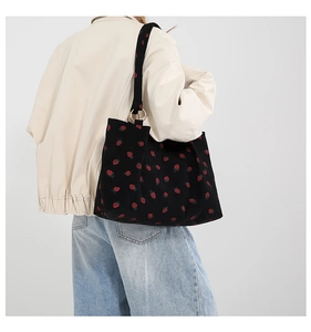 Detail of strawberry pattern on black corduroy tote bag with golden metal ring