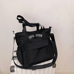 Large black nylon tote bag with DUO NING print on a white suitcase for travel