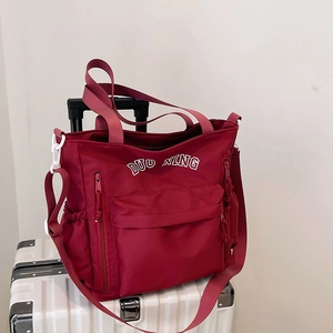Large red nylon tote bag with DUO NING lettering on a suitcase for travel and commuting