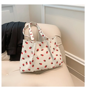 Detail of white corduroy tote bag with strawberry prints and metal ring buckle