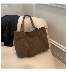 Detail of strawberry pattern on brown corduroy tote bag showing fabric texture and design