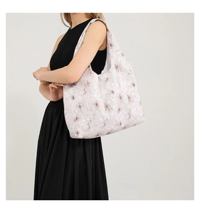 Sac fourre-tout à fleurs porté par un mannequin en robe noire, style sac à bandoulière