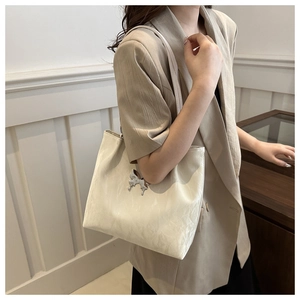 Détail d'un sac cabas blanc crème avec texture plissée nuage et boucle papillon argentée