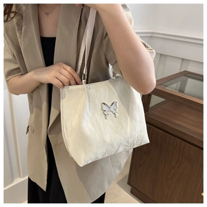 Sac fourre-tout blanc avec texture plissée douce et détail papillon argenté poli