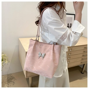 Détail du sac cabas rose avec papillon argenté et texture plissée sur le tissu doux