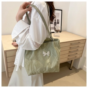 Détail d'un sac cabas plissé vert clair avec un charm papillon argenté en intérieur
