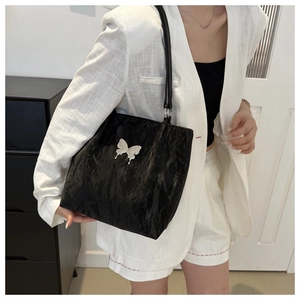 Détail du sac à bandoulière en cuir souple noir avec une boucle papillon argentée