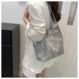 Vue détaillée du sac cabas argenté avec texture plissée métallique et décor papillon