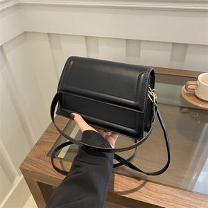 Minimalist black leather crossbody bag with rectangular stitching and gold hardware details