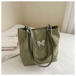 Détail du sac cabas vert sauge avec texture froissée et détail de papillon en métal argenté