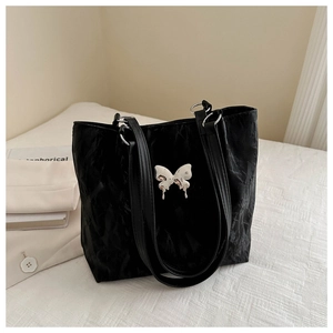 Vue macro d'un sac cabas noir en matière plissée texturée avec boucle papillon argentée