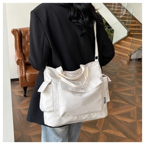 Detail of off-white large capacity tote bag with fashion label and multi-pocket design