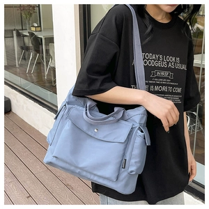 Vue détaillée du grand sac cabas en toile gris-bleu avec large bandoulière et multi-poches