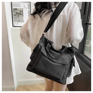 Detail of a black large capacity tote bag with front pocket and adjustable strap