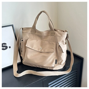 Detail view of khaki canvas tote with large front pocket and adjustable shoulder straps