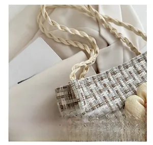 Dettaglio di borsa a secchiello intrecciata beige con grande fiore in tessuto e tracolla