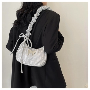 Gros plan sur un sac croissant argenté plissé avec détail papillon métallique Y2K