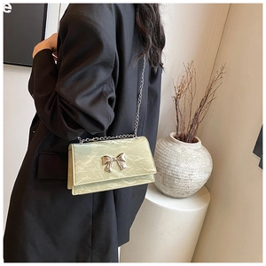 Détail du sac bandoulière vert pistache avec nœud argenté et texture marbrée