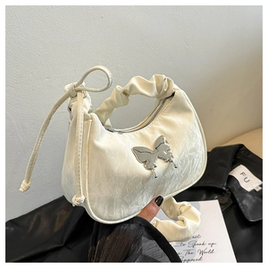 Détail du sac demi-lune plissé crème avec boucle papillon argentée et bandoulière froncée