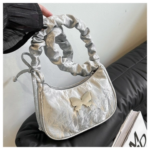 Détail du sac hobo métallisé argenté avec texture plissée et ornement papillon argenté