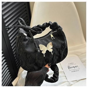 Détail du sac plissé noir avec papillon en métal brillant et poignée à nœud chic