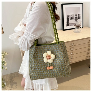 Dettaglio della borsa tote intrecciata multicolore con ciondolo a fiore e pompon arancio