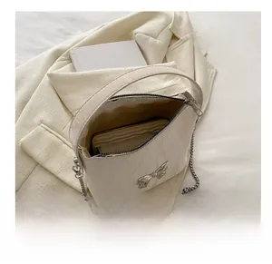 Détail montrant la capacité intérieure du sac crème avec nœud en métal et chaîne