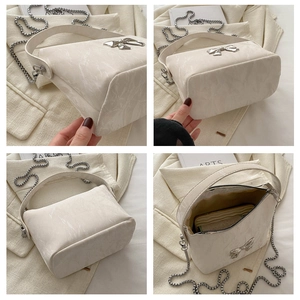 Detail view of cream marble texture handbag with silver bow charm and metal chain