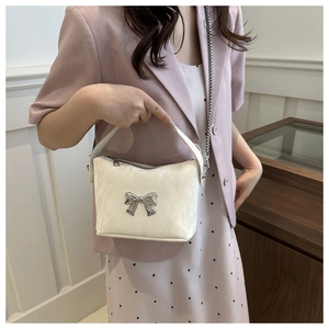 Détail d'un sac à main en cuir PU crème avec nœud en métal argenté et bandoulière chaîne