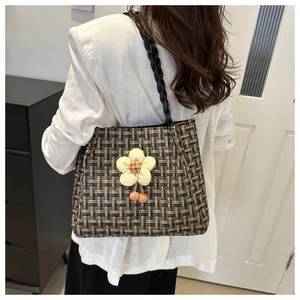Dettaglio della borsa tote in tweed con ciondolo a fiore e manici neri intrecciati