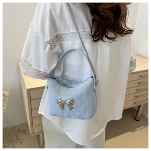 Gros plan d'un sac bandoulière bleu clair plissé avec nœud argenté et bandoulière chaîne