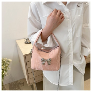 Detailed close-up of pink embossed texture handbag with silver metal bow and chain